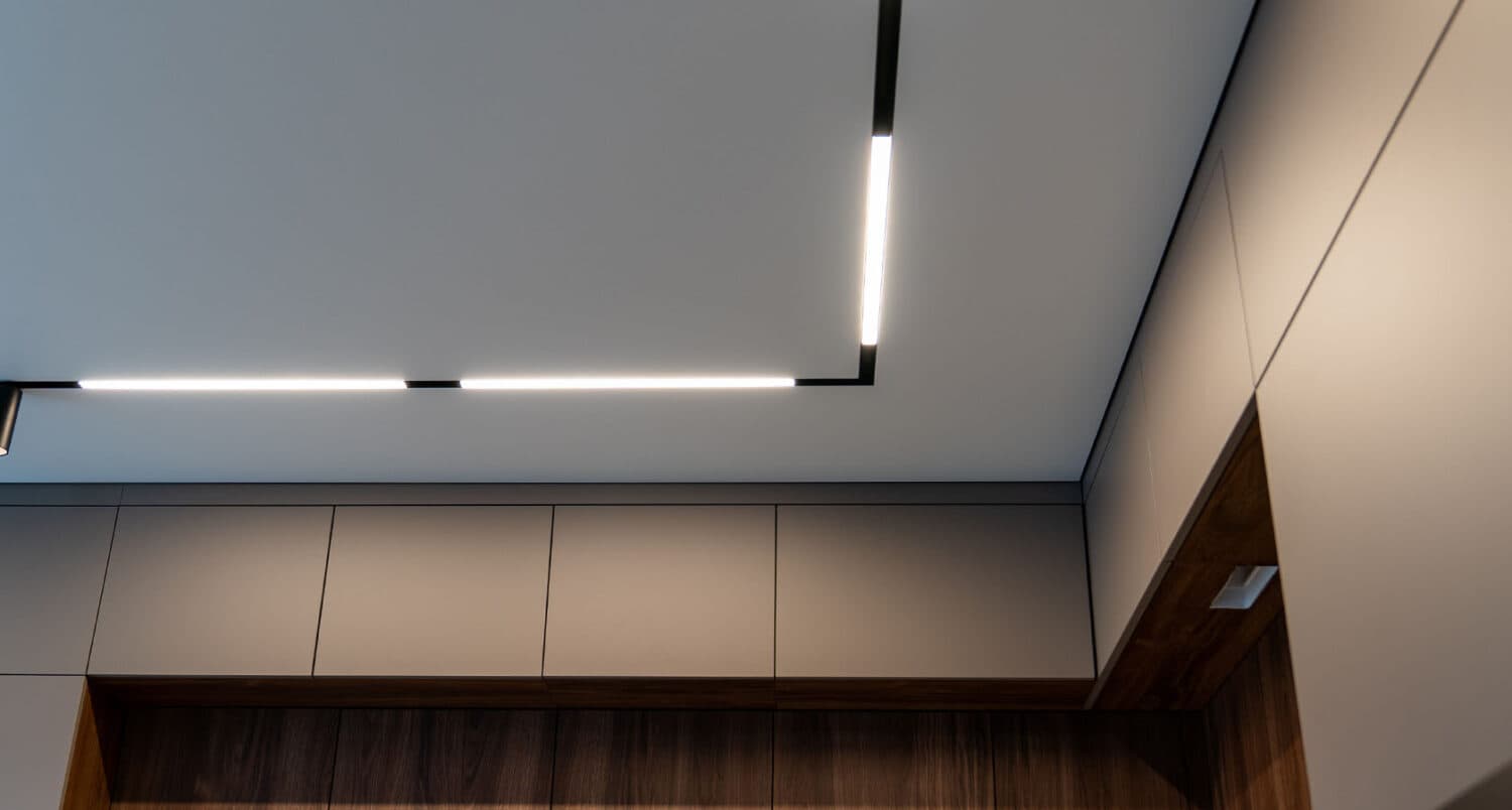 Linie LED încastrată în tavanul extensibil al unei bucătării moderne cu mobilier din lemn