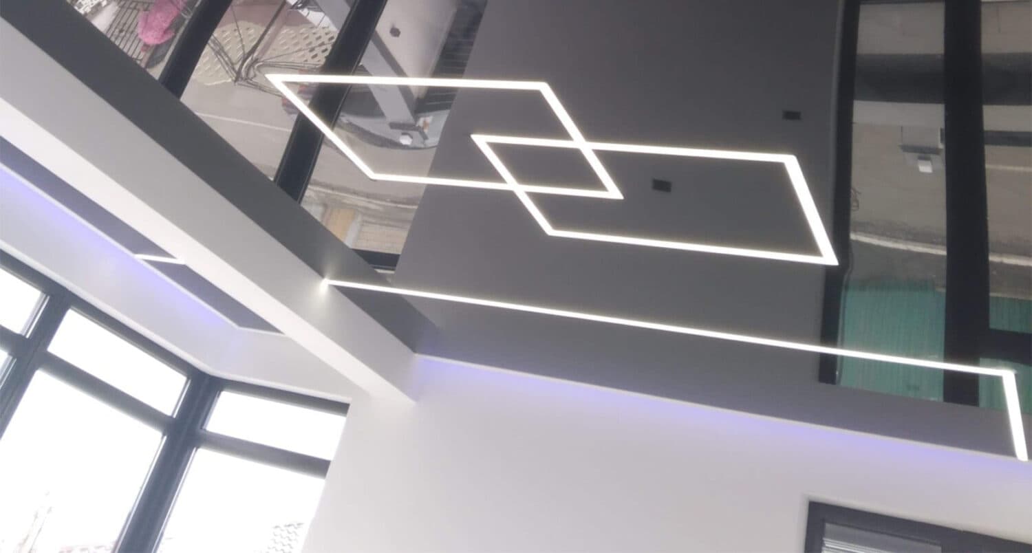 Tavan extensibil negru lucios cu efect de oglindă și linii LED albe dispuse în romburi, într-un spațiu comercial