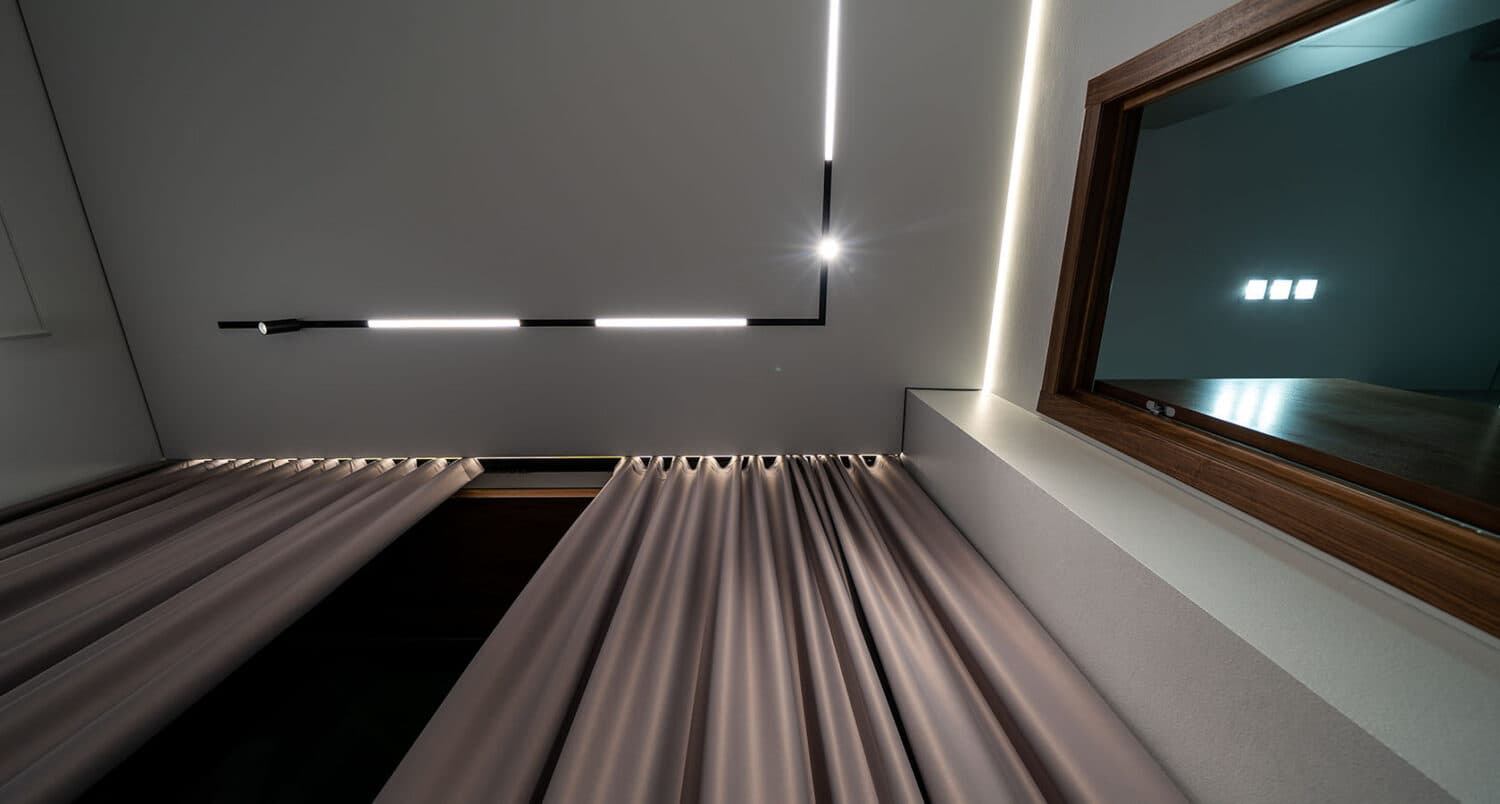 Șină magnetică cu module LED liniare pe tavan extensibil, cu nișă de draperie iluminată cald, într-un dormitor