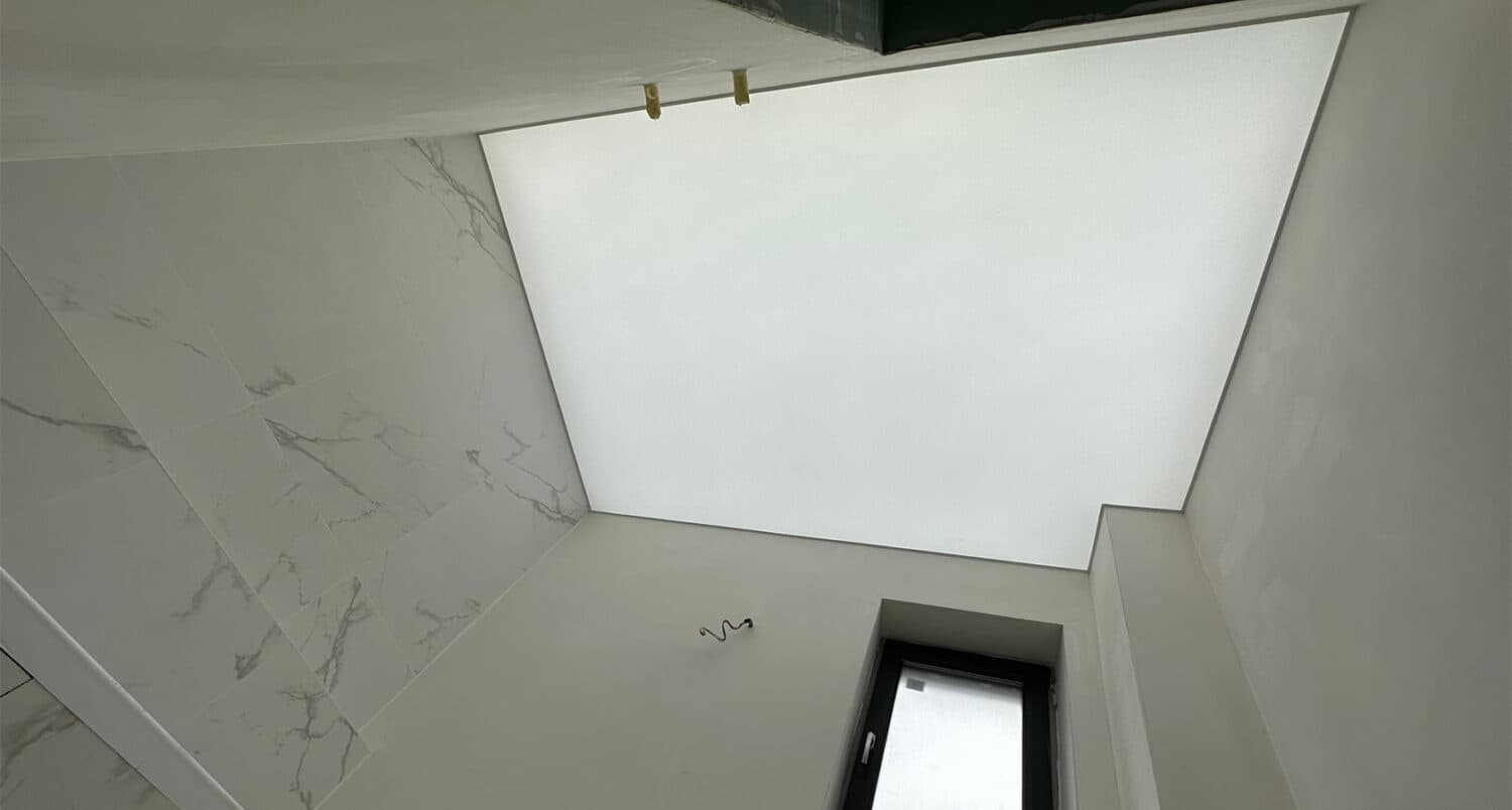 Tavan luminos translucid alb montat într-o baie aflată în finisare, cu plăci de marmură albă